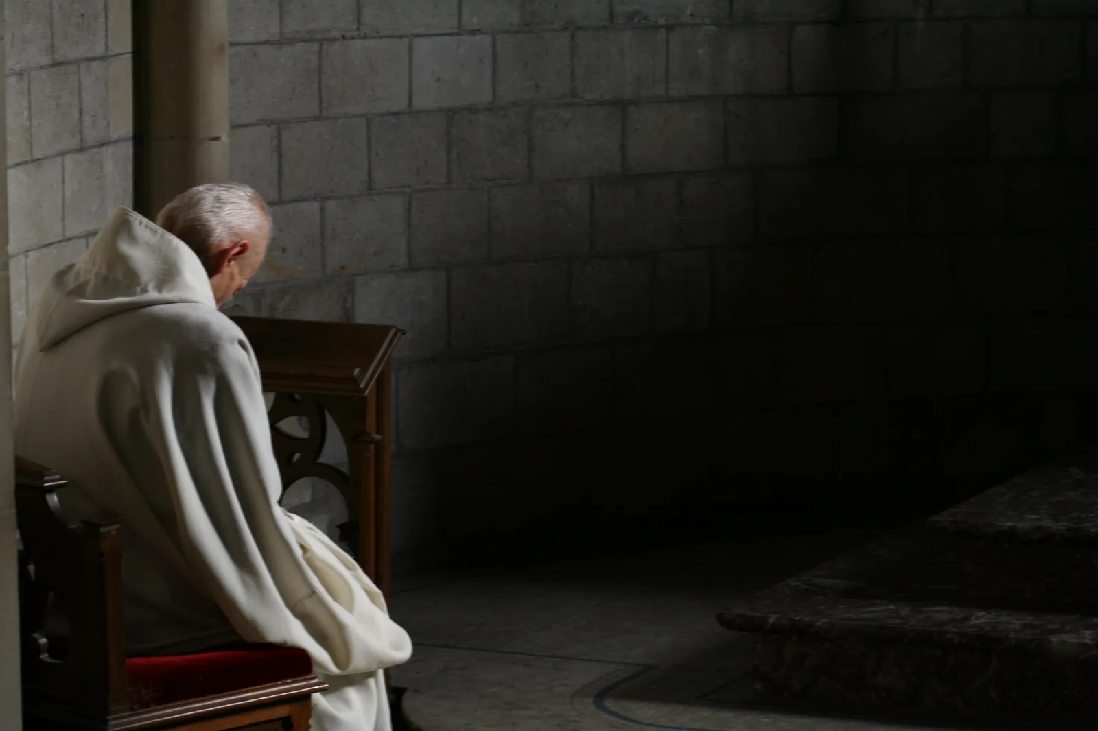 Un frère en prière dans la pénombre de l’église abbatiale