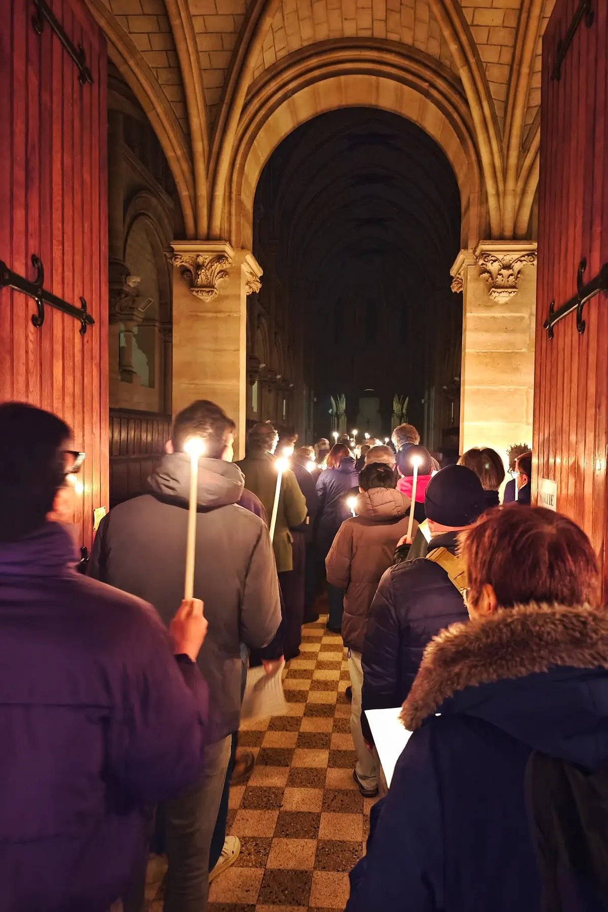Les fidèles en procession dans l’église, un cierge à la main